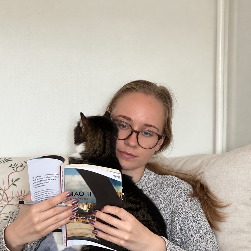Zsófi reading in bed with her cat on her shoulder
